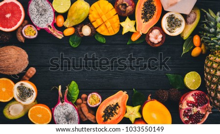 Tropical fruits, papaya, Dragon Fruit, rambutan, tamarind, cactus fruit, avocado, granadilla, carambola, kumquat, mango, mangosteen, passionfruit, coconut. On a wooden background.