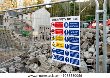 "Site Safety Notice" Sign Attached To Metal Fence In Front Of Building Site