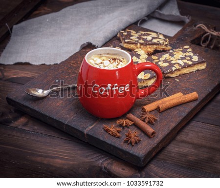 black coffee with marshmallow in a red ceramic mug on a brown wooden table