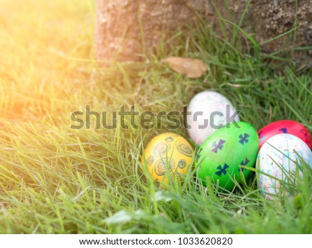 Colorful Easter eggs in grass against blurred green background with small house model on back side.  Spring holidays concept