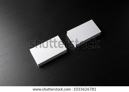 Photo of blank business cards stacks on black wood table background. Template for branding identity.