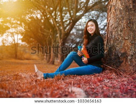young woman sitting and holding a book in the park