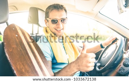 Young hipster fashion model guy driving car with longoboard on spring break summer mood - Happy confident man with thumb up smiling looking at camera - Lens flare sunshine halo with warm bright filter