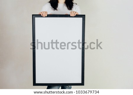 Woman showing and holding empty picture frame in studio shot. Hands holding frame close-up,