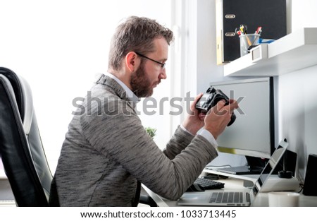 Photographer in home office working with laptop computer and looking at camera