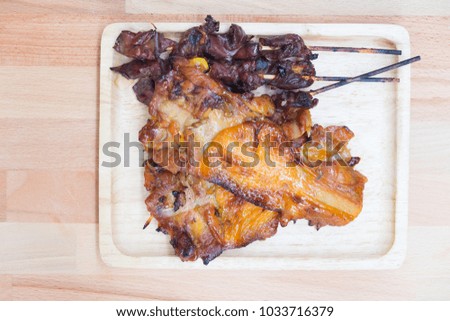 Thai style barbecue chicken meat and entrails on wood tray