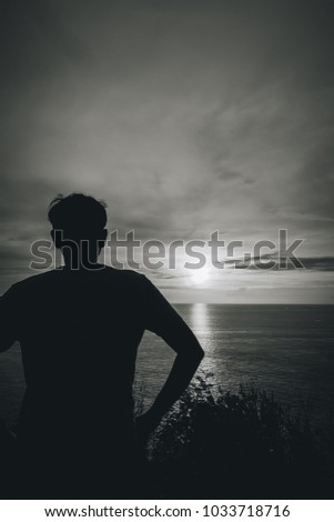 a silhouette shadow image of man standing at the coast watching a scenic beautiful landscape view, sunset on sea the horizon skyline and the sun light reflected on sea , on the holiday vacation trip 