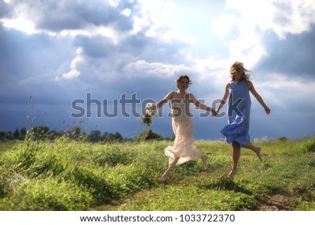 Young girls are walking in the field before the rain