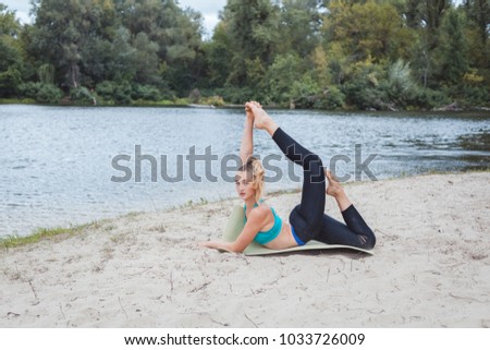 Girl doing sport stretching on the river bank.