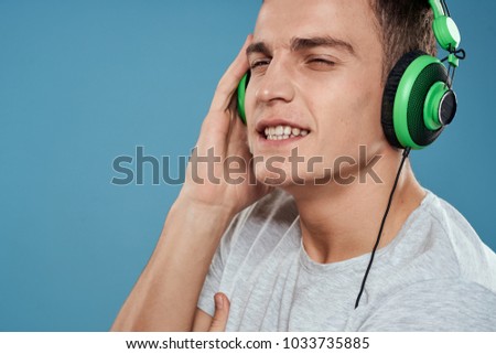 man listening to music with headphones on a blue background                               