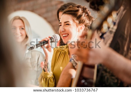 Entertianment at a wedding. A female singer is interacting with the crowd while a man plays an acoustic guitar.  Royalty-Free Stock Photo #1033736767
