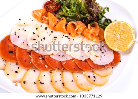 Assorted fish on a plate with lettuce and lemon on a white background.