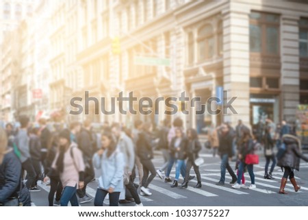 Anonymous people crossing street in SoHo New York City with sunlight in background