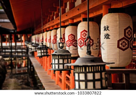 Line of traditional paper Japanese lantern lamps on the Itsukushima Shrine on the Miyajima Island in Hiroshima. 

(Translation of text on the lantern: ''Dedication Lamp'')
