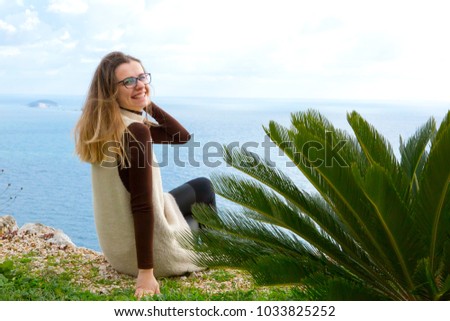 Beautiful girl sitting on top of mountain, in background is wonderful view of blue sea, mountains and sky. Croatia