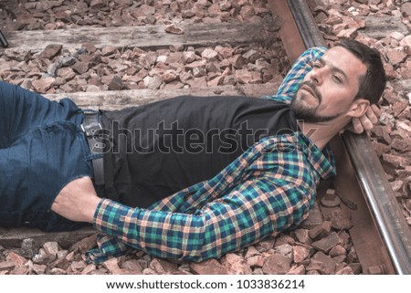 Boy with a thoughtful face and serious attitude. Picture on the train tracks, man dressed casual. Portrait