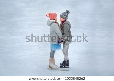 a boy with a girl learns to skate on ice skates on ice, holding hands. The concept of winter entertainment for children. The winter vacation