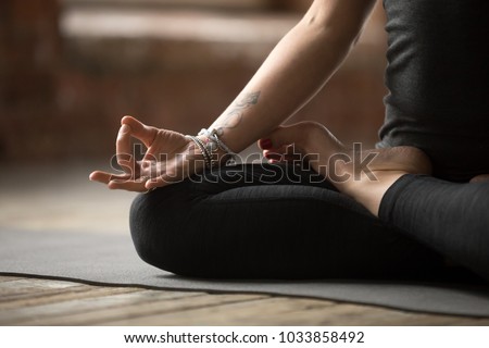 Young sporty woman practicing yoga, doing Padmasana exercise, Lotus pose, with mudra gesture, working out, wearing sportswear, black pants and top, indoor close up, yoga studio Royalty-Free Stock Photo #1033858492