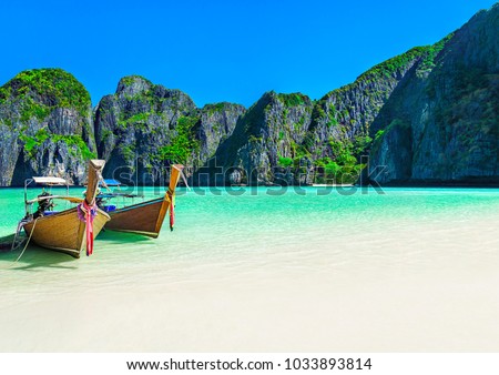 Famous Maya Bay beach at Ko Phi Phi Leh Island with two traditional longtail taxi boats mooring and steep limestone hills in background. Main Thailand tourist attraction, Krabi Province, Andaman Sea Royalty-Free Stock Photo #1033893814