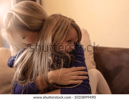 Beautiful young blond mother is hugging her cute little daughter. 
