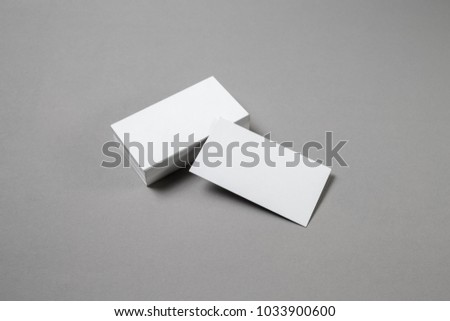 Blank white business cards on grey paper background. Mockup for branding identity. Template for graphic designers portfolios. Top view.
