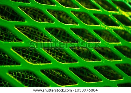Green metal lattice lozenge rhombus close-up, under a fine metal grid.