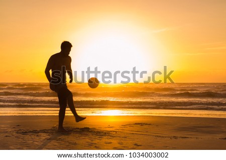 Great concept of soccer, man playing soccer on the beach in golden hour, sunset. Making keepie uppie. Royalty-Free Stock Photo #1034003002