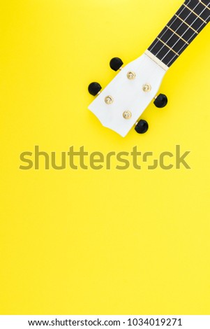 White ukulele on a yellow background and with a place for text. Musical concept. Flat Lay