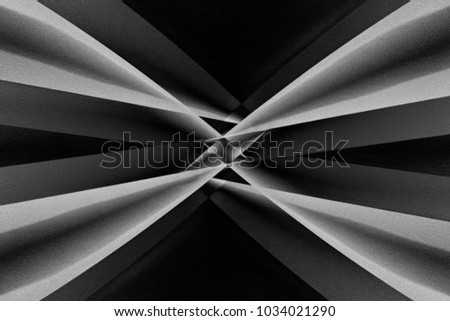 Abstract architecture with distortion effect. Angular girders refracted by small glass prism in center of composition. Contrast black and white photo of modern building in darkness.