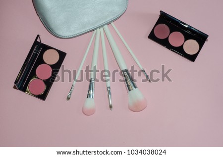 Woman cosmetic bag, make up beauty products on pink background. Makeup brushes and rouge palettes. Decorative cosmetics. Top view, flatlay. Copyplace, place for text
