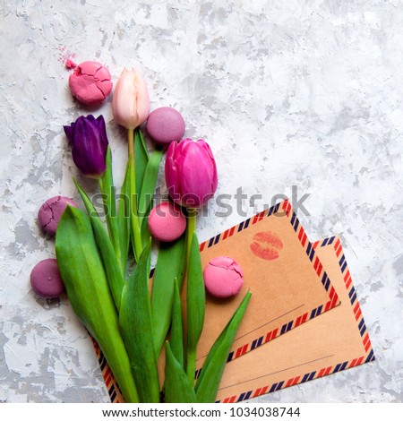 Pink and purple tulips and macarons and vintage kraft envelopes with kiss print on light textured background. Romantic congratulations concept with copy space