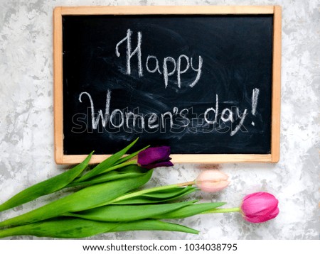 Chalkboard with inscription Happy Women's day and three tulips on light textured background. Women things for 8 march concept