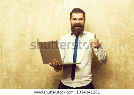 hipster or bearded man with long beard and stylish hair on happy face in tie and white shirt hold laptop on textured beige background, digital marketing and business, agile business, businessman