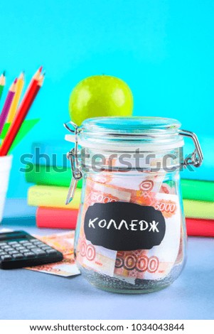 Bank with Russian money, 5000 rubles and a calculator, books on a gray background. Finance, moneybox, education. Text in Russian: college