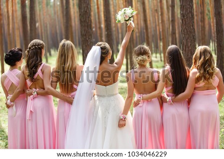 Bride and bridesmaids in pink dresses having fun at wedding day. Happy marriage and wedding party concept Royalty-Free Stock Photo #1034046229