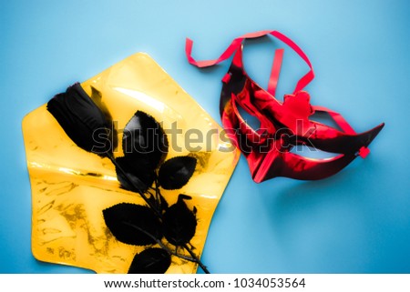 carnival concept, red Venetian mask with black rose on blue background, symbol of sadness and farewells. black rose can also mean a new beginning and rebirth.
