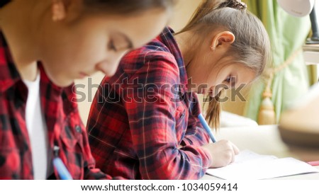 Portrait of 10 years old girl doing homework with sister