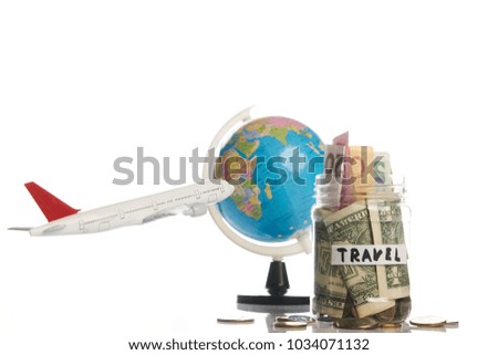 Holidays budget concept. Travel money savings in a glass jar with flying plane toy and world globe map on a white background, close-up