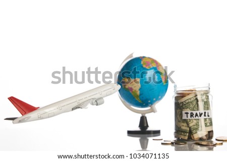 Holidays budget concept. Travel money savings in a glass jar with flying plane toy and world globe map on a white background, close-up