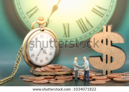 Miniature people: Business man hand shake and stack of coins, wooden dollar with copy space using as background sale, buy, trade, deal, business time concept.
