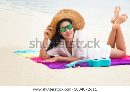 Summer woman relaxing in hipster beach hat and colorful sunglasses. Funky happy girl having fun during travel holidays vacation. Young trendy cool hipster woman lying in the sand.