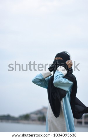 Young asian muslim woman wearing niqab with peaceful expression listen music with headphone