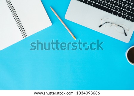 Minimal work space - Creative flat lay photo of workspace desk. Top view office desk with laptop, notebooks and coffee cup on blue color background. Top view with copy space, flat lay photography.