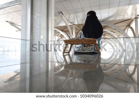 Young asian muslim woman wearing niqab with peaceful expression while reading book