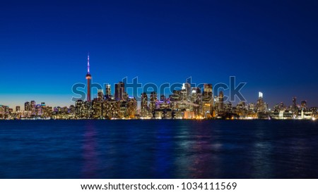 Toronto skyline at night with reflected lights over Lake Ontario.