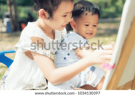 Asian little boy and sister draw together in park. Kids painting and drawing. Children paint with paintbrush color and pencils. Art and crafts for toddler and preschooler.

