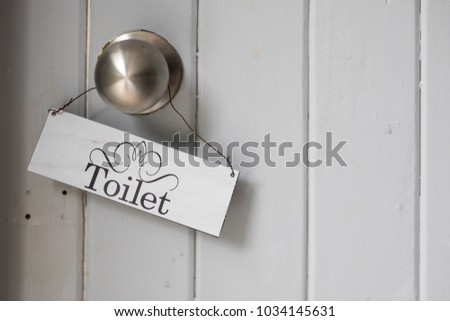 Aged toilet sign hanging on a door handle