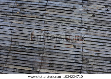 Close up exterior view of a bamboo palisade in a rural garden. Pattern made of parallel old grey wooden elements. Rough stripped texture. Abstract natural image with long grey and brown thin lines.