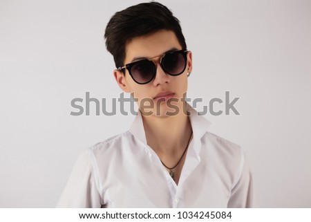 young Asian guy in white shirt, sunglasses looking directly on white background.horizontal photo