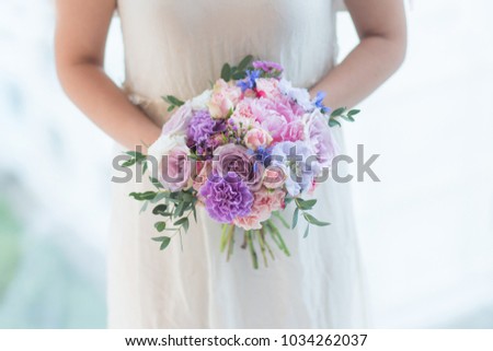 Gentle bridal bouquet in the hands. Fresh mixed flowers bouquet of pink peony, blue scabiosa, carnation, white spray roses, memory lane roses, violet waxflower, cornflower and eucalyptus